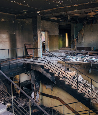 Severe fire damage showing charred walls and structural harm inside a building